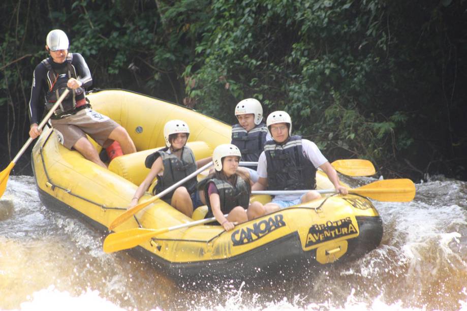 Jovens praticando rafting com monitor da Canoar, no Acampamento Fazenda Estância Peraltas, Brotas (SP)