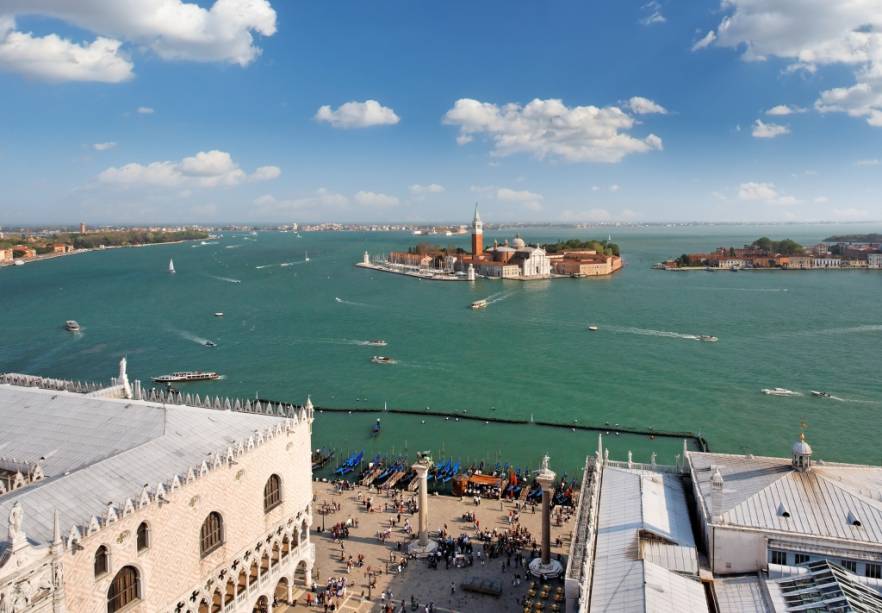 Vista geral da laguna de <a href="https://viajeaqui.abril.com.br/cidades/italia-veneza" rel="Veneza">Veneza</a>. Em primeiro plano, a Piazzeta, com as colunas de São Teodoro e São Marcos e o Palazzo Ducale. Ao longe, as ilhas de San Giorgio Maggiore e Giudecca