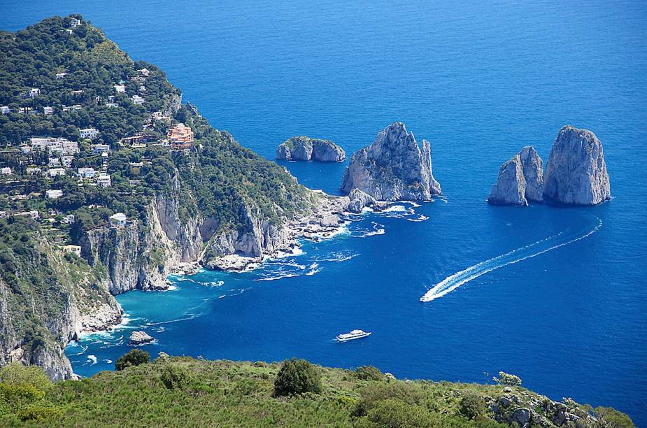 <a href="https://viajeaqui.abril.com.br/cidades/italia-capri" target="_blank" rel="noopener"><strong>Capri </strong></a> Cheia de história, Capri é um bom exemplo da atmosfera mediterrânea. Hoje, praticamente toda a cidade é voltada ao turismo. É badalada e costuma receber celebridades. A ilha é pequena, tem um pouco mais do que a metade do tamanho de Fernando de Noronha. A vegetação que cobre parte da ilha combina muito bem com o azul do mar que a cerca. <em><a href="https://www.booking.com/searchresults.en-gb.html?aid=332455&lang=en-gb&sid=eedbe6de09e709d664615ac6f1b39a5d&sb=1&src=searchresults&src_elem=sb&error_url=https%3A%2F%2Fwww.booking.com%2Fsearchresults.en-gb.html%3Faid%3D332455%3Bsid%3Deedbe6de09e709d664615ac6f1b39a5d%3Bclass_interval%3D1%3Bdest_id%3D-126145%3Bdest_type%3Dcity%3Bdtdisc%3D0%3Bfrom_sf%3D1%3Bgroup_adults%3D2%3Bgroup_children%3D0%3Binac%3D0%3Bindex_postcard%3D0%3Blabel_click%3Dundef%3Bno_rooms%3D1%3Boffset%3D0%3Bpostcard%3D0%3Braw_dest_type%3Dcity%3Broom1%3DA%252CA%3Bsb_price_type%3Dtotal%3Bsearch_selected%3D1%3Bsrc%3Dsearchresults%3Bsrc_elem%3Dsb%3Bss%3DRavello%252C%2520%25E2%2580%258BCampania%252C%2520%25E2%2580%258BItaly%3Bss_all%3D0%3Bss_raw%3DRavello%3Bssb%3Dempty%3Bsshis%3D0%3Bssne_untouched%3DAmalfi%2520Coast%26%3B&ss=Capri+Island%2C+%E2%80%8BItaly&ssne=Ravello&ssne_untouched=Ravello&city=-126145&checkin_monthday=&checkin_month=&checkin_year=&checkout_monthday=&checkout_month=&checkout_year=&no_rooms=1&group_adults=2&group_children=0&highlighted_hotels=&from_sf=1&ss_raw=Capri&ac_position=0&ac_langcode=en&dest_id=1434&dest_type=region&place_id_lat=40.551666&place_id_lon=14.232678&search_pageview_id=32b9915af84f06c9&search_selected=true&search_pageview_id=32b9915af84f06c9&ac_suggestion_list_length=5&ac_suggestion_theme_list_length=0" target="_blank" rel="noopener">Busque hospedagens em Capri no Booking.com</a></em>