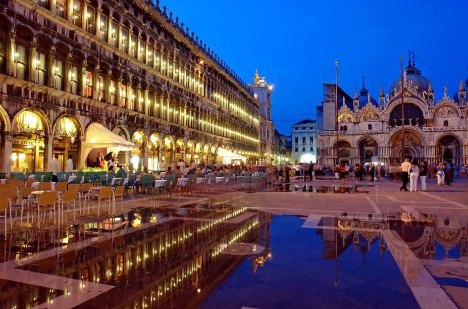 <strong>Piazza San Marco – <a href="https://preprod.viagemeturismo.abril.com.br/cidades/veneza-15/" target="_blank" rel="noopener">Veneza</a> – <a href="https://preprod.viagemeturismo.abril.com.br/paises/italia-2/" target="_blank" rel="noopener">Itália  </a></strong> Uma das mais belas e imponentes praças do mundo. A Piazza é um dos melhores pontos para curtir a paisagem e ver o povo passando por Veneza, mas também um dos lugares mais fortemente afetados durante as enchentes regulares da cidade, que são mais comuns durante o inverno. Para ver os museus que ficam na praça, é importante chegar cedo, antes da invasão de turistas. Sugerimos voltar à tardinha para o pôr do sol e quem sabe um café na <a href="https://viajeaqui.abril.com.br/estabelecimentos/italia-veneza-restaurante-caffe-florian" target="_blank" rel="noopener">Florian</a>, a cafeteria mais antiga da Itália. À noite, sua atmosfera é simplesmente mágica. Para conferir a melhor vista de Veneza, suba o elevador da <strong>torre do campanário </strong>que fica em um dos cantos da praça. Com sua primeira versão erguida no século 9, a torre desmoronou em 1902 e foi reconstruída de acordo com o projeto do século 16 <a href="https://www.booking.com/searchresults.pt-br.html?aid=332455&sid=d98f25c4d6d5f89238aebe98e11a09ba&sb=1&src=index&src_elem=sb&error_url=https%3A%2F%2Fwww.booking.com%2Findex.pt-br.html%3Faid%3D332455%3Bsid%3Dd98f25c4d6d5f89238aebe98e11a09ba%3Bsb_price_type%3Dtotal%26%3B&ss=Veneza%2C+Veneto%2C+It%C3%A1lia&is_ski_area=&ssne=Rio+de+Janeiro&ssne_untouched=Rio+de+Janeiro&checkin_year=&checkin_month=&checkout_year=&checkout_month=&group_adults=2&group_children=0&no_rooms=1&b_h4u_keep_filters=&from_sf=1&ss_raw=veneza&ac_position=0&ac_langcode=xb&ac_click_type=b&dest_id=-132007&dest_type=city&iata=VCE&place_id_lat=45.433891&place_id_lon=12.338505&search_pageview_id=ef6378843535029d&search_selected=true&search_pageview_id=ef6378843535029d&ac_suggestion_list_length=5&ac_suggestion_theme_list_length=0" target="_blank" rel="noopener"><em>Busque hospedagem em Veneza</em></a>