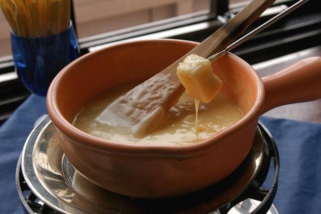 <strong>Fondue, <a href="https://viajeaqui.abril.com.br/paises/suica" rel="Suíça" target="_blank">Suíça</a></strong><br /> Prato nacional da Suíça, a fondue é uma das mais lúdicas experiências gastronômicas que existem. É só o tempo esfriar um pouquinho para os restaurantes de <a href="https://viajeaqui.abril.com.br/cidades/br-rs-gramado" rel="Gramado" target="_blank">Gramado (RS)</a>, <a href="https://viajeaqui.abril.com.br/cidades/br-rj-nova-friburgo" rel="Nova Friburgo" target="_blank">Nova Friburgo (RJ)</a> e <a href="https://viajeaqui.abril.com.br/cidades/br-sp-campos-do-jordao" rel="Campos do Jordão" target="_blank">Campos do Jordão (SP)</a> lotarem com famílias e amigos, todos mergulhando seus espetinhos no <em>rechaud</em>. A mistura cremosa pode levar vários tipos de queijo, como o gruyére e o ementhal, quase sempre perfumados com um pouco de vinho branco e <em>kirsch</em>, um destilado de cereja. Apesar do imaginário popular remeter sua origem às montanhas alpinas, o conceito de queijo derretido provavelmente originou-se em algum restaurante urbano. Menos romântico, mais provável. Seja como for, é uma pequena e alegre celebração coletiva <strong>Fondue, <a href="https://viajeaqui.abril.com.br/paises/suica" rel="Suíça" target="_blank">Suíça</a></strong><br /> Prato nacional da Suíça, a fondue é uma das mais lúdicas experiências gastronômicas que existem. É só o tempo esfriar um pouquinho para os restaurantes de <a href="https://viajeaqui.abril.com.br/cidades/br-rs-gramado" rel="Gramado" target="_blank">Gramado (RS)</a>, <a href="https://viajeaqui.abril.com.br/cidades/br-rj-nova-friburgo" rel="Nova Friburgo" target="_blank">Nova Friburgo (RJ)</a> e <a href="https://viajeaqui.abril.com.br/cidades/br-sp-campos-do-jordao" rel="Campos do Jordão" target="_blank">Campos do Jordão (SP)</a> lotarem com famílias e amigos, todos mergulhando seus espetinhos no <em>rechaud</em>. A mistura cremosa pode levar vários tipos de queijo, como o gruyére e o ementhal, quase sempre perfumados com um pouco de vinho branco e <em>kirsch</em>, um destilado de cereja. Apesar do imaginário popular remeter sua origem às montanhas alpinas, o conceito de queijo derretido provavelmente originou-se em algum restaurante urbano. Menos romântico, mais provável. Seja como for, é uma pequena e alegre celebração coletiva