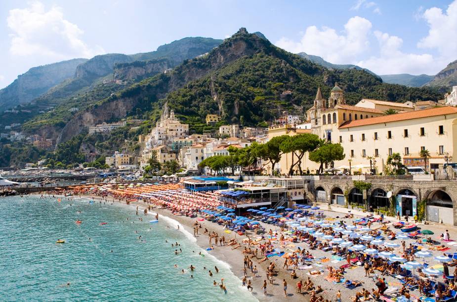 <a href="https://viajeaqui.abril.com.br/cidades/italia-amalfi" target="_blank" rel="noopener"><strong>Amalfi </strong></a> É uma das maravilhas da <a href="https://viajeaqui.abril.com.br/cidades/italia-costa-amalfitana" target="_blank" rel="noopener">Costa Amalfitana</a>. Pequenina, vinte minutos de caminhada levam você de uma ponta até a outra da praia. Sendo assim, podemos dizer que a beleza do lugar é inversamente proporcional ao seu tamanho. <a href="https://www.booking.com/searchresults.en-gb.html?aid=332455&lang=en-gb&sid=eedbe6de09e709d664615ac6f1b39a5d&sb=1&src=searchresults&src_elem=sb&error_url=https%3A%2F%2Fwww.booking.com%2Fsearchresults.en-gb.html%3Faid%3D332455%3Bsid%3Deedbe6de09e709d664615ac6f1b39a5d%3Bcity%3D-131408%3Bclass_interval%3D1%3Bdest_id%3D-125592%3Bdest_type%3Dcity%3Bdtdisc%3D0%3Bfrom_sf%3D1%3Bgroup_adults%3D2%3Bgroup_children%3D0%3Binac%3D0%3Bindex_postcard%3D0%3Blabel_click%3Dundef%3Bno_rooms%3D1%3Boffset%3D0%3Bpostcard%3D0%3Braw_dest_type%3Dcity%3Broom1%3DA%252CA%3Bsb_price_type%3Dtotal%3Bsearch_selected%3D1%3Bsrc%3Dsearchresults%3Bsrc_elem%3Dsb%3Bss%3DPositano%252C%2520%25E2%2580%258BCampania%252C%2520%25E2%2580%258BItaly%3Bss_all%3D0%3Bss_raw%3DPositano%3Bssb%3Dempty%3Bsshis%3D0%3Bssne_untouched%3DTropea%26%3B&ss=Amalfi+Coast%2C+%E2%80%8BItaly&ssne=Positano&ssne_untouched=Positano&city=-125592&checkin_monthday=&checkin_month=&checkin_year=&checkout_monthday=&checkout_month=&checkout_year=&no_rooms=1&group_adults=2&group_children=0&highlighted_hotels=&from_sf=1&ss_raw=Amalfi&ac_position=0&ac_langcode=en&dest_id=1681&dest_type=region&place_id_lat=40.64137&place_id_lon=14.597403&search_pageview_id=6b9c91340f460009&search_selected=true&search_pageview_id=6b9c91340f460009&ac_suggestion_list_length=5&ac_suggestion_theme_list_length=0" target="_blank" rel="noopener"><em>Busque hospedagens em Amalfi no Booking.com</em></a>