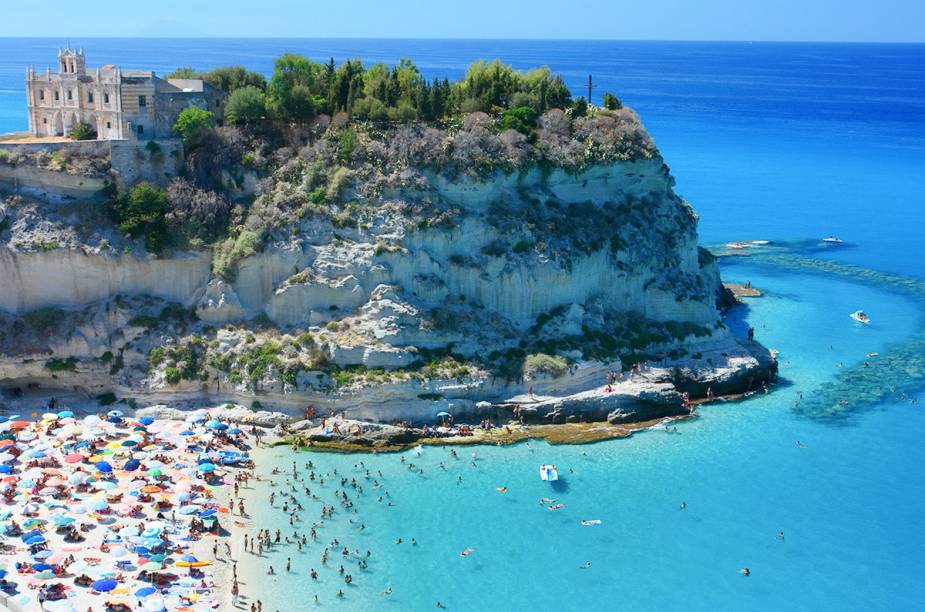 <strong>Praia de Tropea, Calábria, <a href="https://viajeaqui.abril.com.br/paises/italia" rel="Itália" target="_self">Itália</a> </strong>                Um precipício compõe a paisagem do cenário, proporcionando uma belíssima visão ao visitante, sobretudo no pôr do sol. Por aqui, as águas cristalinas impressionam, convidando a passeios como o de pedalinho. O entorno da praia revela uma cidade antiga, repleta de construções históricas. Por aqui, também há muitos bons restaurantes de frutos do mar                <em><a href="https://www.booking.com/city/it/tropea.pt-br.html?sid=5b28d827ef00573fdd3b49a282e323ef;dcid=1?aid=332455&label=viagemabril-as-mais-belas-praias-do-mediterraneo" rel="Veja preços de hotéis em Tropea no Booking.com" target="_blank">Veja preços de hotéis em Tropea no Booking.com</a></em>