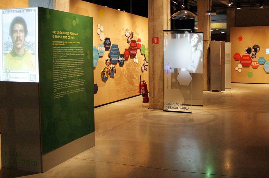 No fundo da imagem, é possível ver uma das atrações mais divertidas da exposição: um chuveiro de mentirinha, em que o visitante pode ouvir a voz de jogadores cantando, como se estivesse dentro do vestiário da seleção brasileira