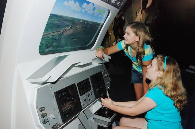 Crianças brincam em um simulador de pouso de ônibus espaciais no Space Shuttle Atlantis, uma das atrações do Kennedy Space Center, no Cabo Canaveral Crianças brincam em um simulador de pouso de ônibus espaciais no Space Shuttle Atlantis, uma das atrações do Kennedy Space Center, no Cabo Canaveral
