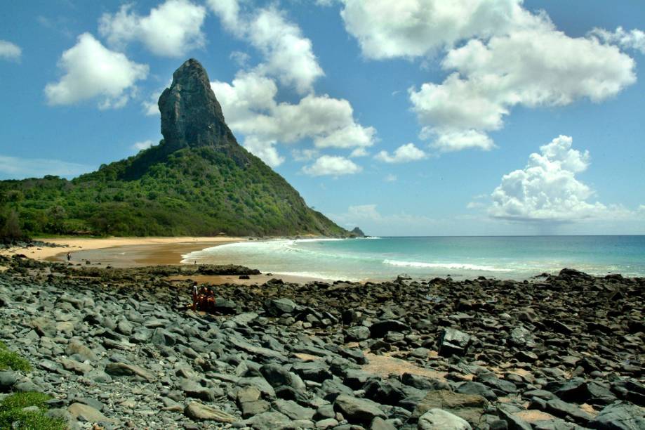 <a href="https://viajeaqui.abril.com.br/estabelecimentos/br-pe-fernando-de-noronha-atracao-praia-da-conceicao"><strong>Praia da Conceição</strong></a>Esta praia tem algo raro em Noronha: um bar pé na areia, o Duda Rei. Tome uma cervejinha e belisque um queijo coalho grelhado enquanto avista o Morro do Pico, faça uma caminhada pela extensa faixa de areia e, se a maré estiver baixa, explore as piscinas naturais que se formam no lado direito da praia. De abril a novembro, o mar fica calmo, mas de dezembro a março a praia é dos surfistas, com ondas de 1,5 metro. Sorte de quem estiver hospedado na Vila do Trinta ou na Vila dos Remédios, que consegue vir até a Praia da Conceição a pé. <a href="https://viajeaqui.abril.com.br/estabelecimentos/br-pe-fernando-de-noronha-atracao-praia-da-conceicao"><strong>Praia da Conceição</strong></a>Esta praia tem algo raro em Noronha: um bar pé na areia, o Duda Rei. Tome uma cervejinha e belisque um queijo coalho grelhado enquanto avista o Morro do Pico, faça uma caminhada pela extensa faixa de areia e, se a maré estiver baixa, explore as piscinas naturais que se formam no lado direito da praia. De abril a novembro, o mar fica calmo, mas de dezembro a março a praia é dos surfistas, com ondas de 1,5 metro. Sorte de quem estiver hospedado na Vila do Trinta ou na Vila dos Remédios, que consegue vir até a Praia da Conceição a pé.