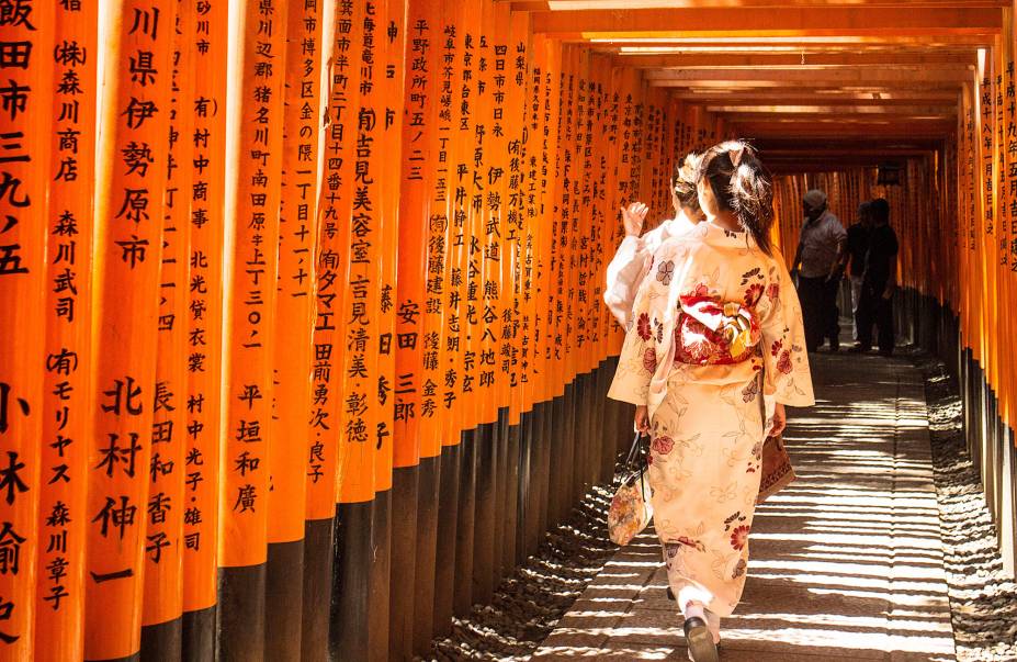 <strong>Fushimi Inari Taisha </strong> Uma das visões mais icônicas da cidade – popularizada pela cena do filme “Memórias de uma Geisha” - é o túnel formado pelos tradicionais portões vermelhos (chamados torii), que guiam seus visitantes por uma rota de peregrinação de aproximadamente 2 horas por uma montanha. Cada um dos torii foi doado por donos de negócios, que pedem bênçãos ao kami (divindade) Inari, que dá nome à montanha e que é o deus do arroz (que na cultura japonesa significa riqueza material). <strong>Fushimi Inari Taisha </strong> Uma das visões mais icônicas da cidade – popularizada pela cena do filme “Memórias de uma Geisha” - é o túnel formado pelos tradicionais portões vermelhos (chamados torii), que guiam seus visitantes por uma rota de peregrinação de aproximadamente 2 horas por uma montanha. Cada um dos torii foi doado por donos de negócios, que pedem bênçãos ao kami (divindade) Inari, que dá nome à montanha e que é o deus do arroz (que na cultura japonesa significa riqueza material).