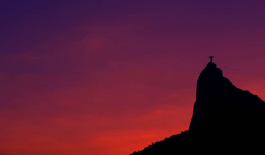 O Cristo Redentor, no Rio de Janeiro (RJ), envolto por pássaros e pelos tons do fim de tarde.