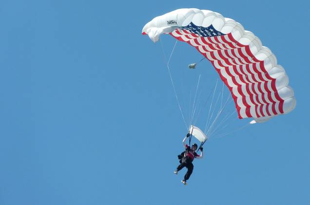Um dos paraquedas é decorado com a bandeira dos Estados Unidos; neste momento, o hino do país saiu em alto e bom som dos alto-falantes e ecoou pelo aeroporto, completamente silencioso e patriótico Um dos paraquedas é decorado com a bandeira dos Estados Unidos; neste momento, o hino do país saiu em alto e bom som dos alto-falantes e ecoou pelo aeroporto, completamente silencioso e patriótico