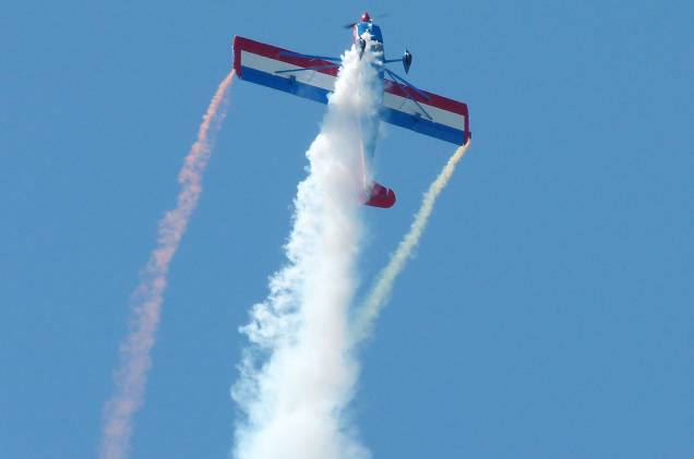 O avião, que só comporta o piloto, sem passageiros, fez manobras com fumaça nas cores da bandeira dos Estados Unidos O avião, que só comporta o piloto, sem passageiros, fez manobras com fumaça nas cores da bandeira dos Estados Unidos