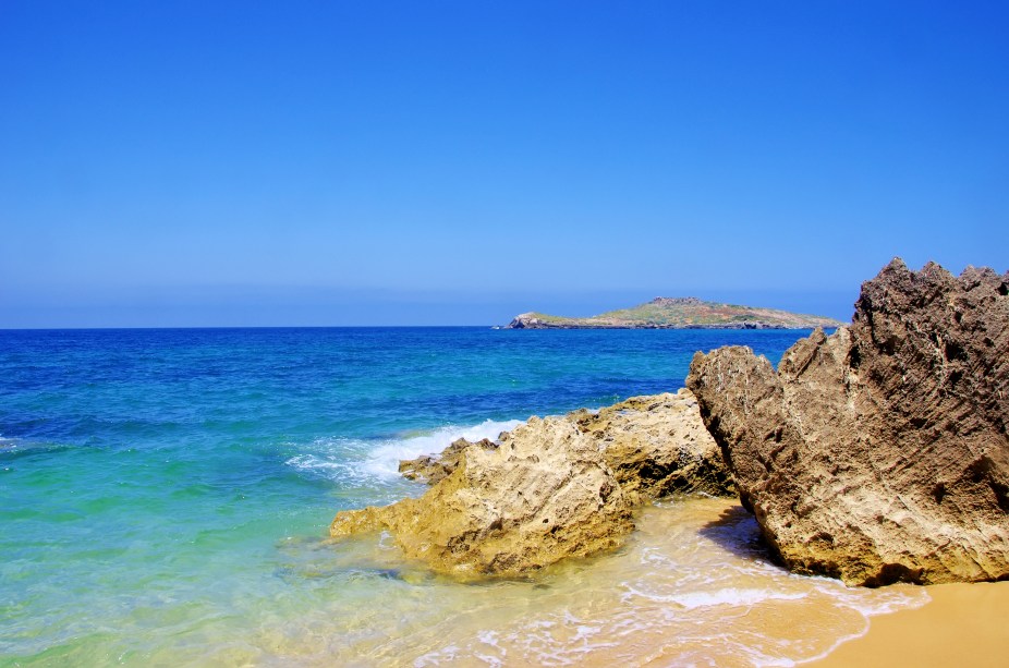 Entre as várias praias de Porto Covo (e também de sua ilha, a do Pessegueiro), a escolhida para ser a queridinha dos turistas é a Praia Grande. Isso não é à toa, porque os tons de azul de suas águas, as formações rochosas e seu amplo espaço na areia, fazem dela dona de uma beleza excepcional. <a href="https://www.booking.com/city/pt/setubal.html?aid=332455&label=viagemabril-praiasportugal" target="_blank" rel="noopener noreferrer"><em>Reserve o seu hotel em Setúbal através do Booking.com</em></a>