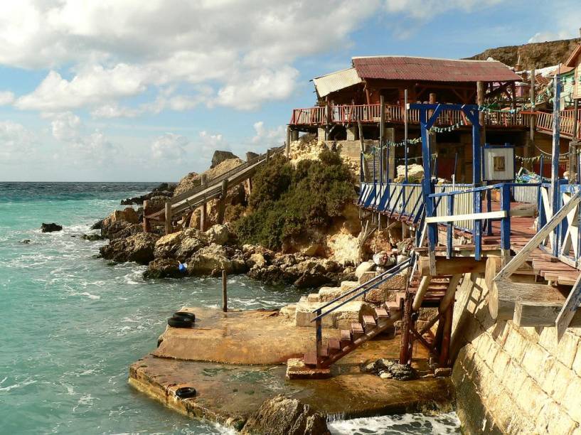 As águas esverdeadas do Mediterrâneo emolduram o cenário com casas de madeira coloridas