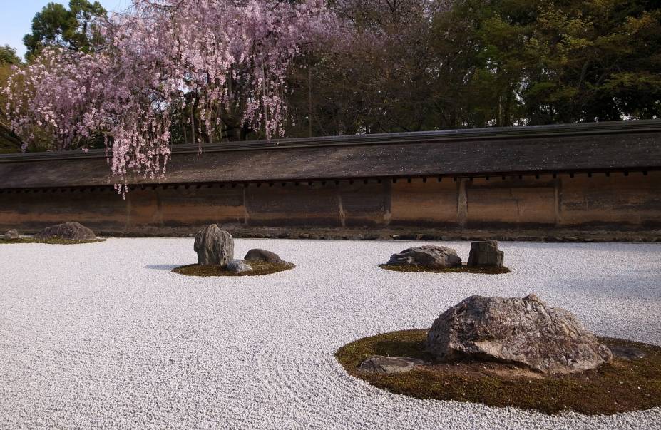 <strong>Ryoan-ji </strong> Localizado na parte nordeste da cidade, o templo também é Patrimônio Mundial da Humanidade pela UNESCO e tem destaque para seu jardim de pedras, o mais famoso do Japão. Apesar de sua história e significado não serem claros, o jardim é considerado uma obra prima desta forma de arte japonesa, que vem do zen budismo: as pedras são cuidadosamente arranjadas em um terreno forrado de cascalho com linhas desenhadas, criando um design que deve reproduzir a essência da natureza e ajudar na meditação zazen. Neste jardim, 15 pedras foram posicionadas de tal maneira que não importa a partir de que ponto se olha, somente 14 serão visíveis. Reza a lenda que só é possível avistar todas as pedras ao mesmo tempo quando o praticante do zen budismo atingir o nirvana.