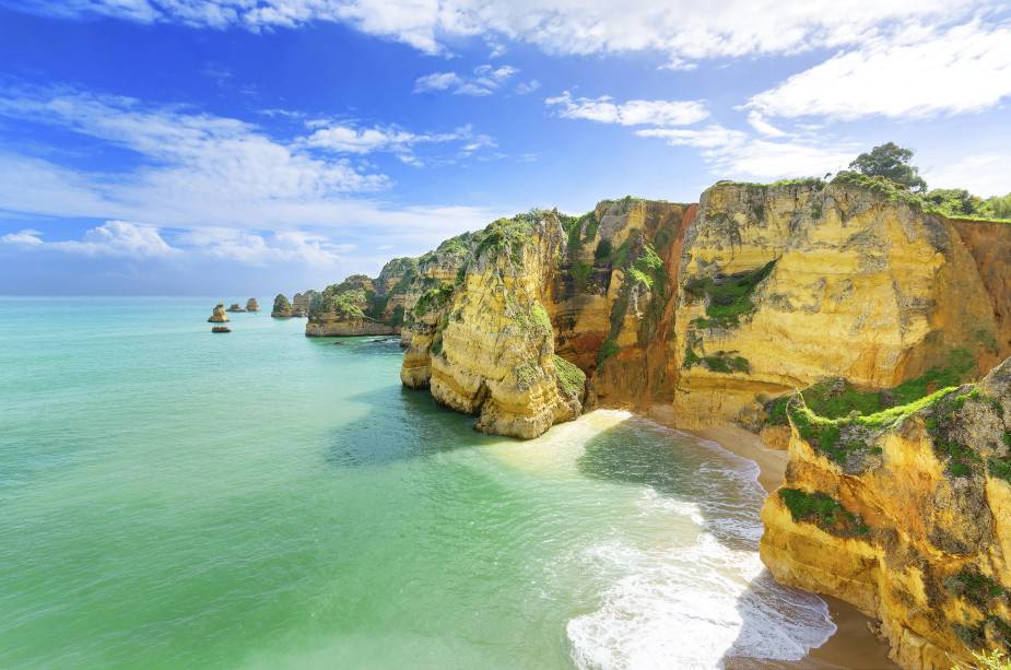 <strong>Ponta da Piedade, Lagos, Algarve, <a href="https://viajeaqui.abril.com.br/paises/portugal" rel="Portugal" target="_self">Portugal</a></strong>                Com pouco mais de 18 mil habitantes, a região de Lagos é repleta de casinhas históricas bem conservadas, além de fornecer uma vida noturna e cultural bem completa. O trecho da Ponta da Piedade é um dos mais deslumbrantes da costa litorânea do país, com grutas e formações rochosas. Uma das boas pedidas é fazer um passeio de barco pelos seus cenários, marcados por águas cristalinas                <em><a href="https://www.booking.com/city/pt/lagos.pt-br.html?sid=5b28d827ef00573fdd3b49a282e323ef;dcid=1?aid=332455&label=viagemabril-as-mais-belas-praias-do-mediterraneo" rel="Veja preços de hotéis em Lagos no Booking.com" target="_blank">Veja preços de hotéis em Lagos no Booking.com</a></em>