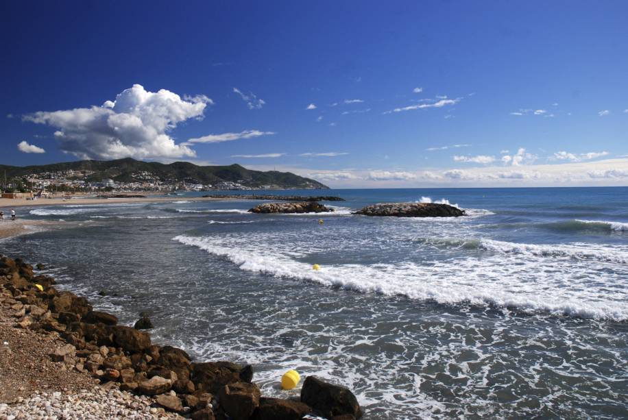 <strong>Sitges, Catalunha, <a href="https://viajeaqui.abril.com.br/paises/espanha" rel="Espanha" target="_self">Espanha</a></strong>                    Há quem diga que os cenários de Sitges tem um quê de <a href="https://viajeaqui.abril.com.br/cidades/br-rj-buzios" rel="Búzios" target="_self">Búzios</a>, graças à combinação de praias com uma boa infraestrutura de lojas e restaurantes. Seus trechos litorâneos são limpos e super seguros – e muitos deles são conhecidos por serem <em>gay friendly</em>. Durante o Carnaval, há festas badaladas regadas a música eletrônica, que tornam a cidade bem frequentada                    <em><a href="https://www.booking.com/city/es/sitges.pt-br.html?sid=5b28d827ef00573fdd3b49a282e323ef;dcid=1?aid=332455&label=viagemabril-as-mais-belas-praias-do-mediterraneo" rel="Veja preços de hotéis em Sitges no Booking.com" target="_blank">Veja preços de hotéis em Sitges no Booking.com</a></em>