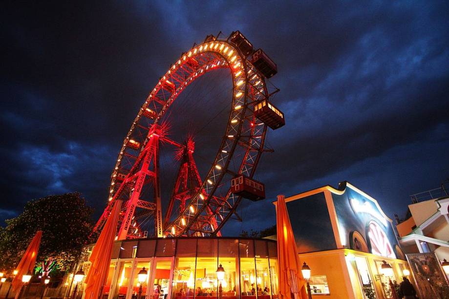 Wiener Riesenrad significa literalmente “roda-gigante vienense”. Foi construída em 1897 no parque de diversões Wurstelprater de <a href="https://viajeaqui.abril.com.br/cidades/austria-viena" target="_self">Viena</a>, na Áustria, e por mais de 60 anos levou o título de maior do mundo. Hoje não parece tão imponente, nem chega a 65 metros de altura, mas é uma sobrevivente: em 1916 autorizaram a sua demolição, mas faltaram fundos para fazer o serviço e decidiram mantê-la ali, sem incomodar ninguém. Com a chegada da Segunda Guerra Mundial, sofreu danos – das 30 gôndolas originais, só sobraram 15. Mas continua como sempre, firme e forte, sendo um dos principais atrativos turísticos da região