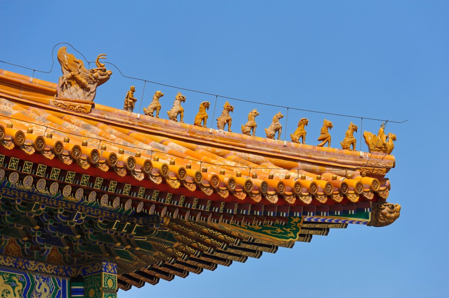 Motivos decorativos em telhado na Cidade Proibida, Pequim, China. Esse tipo de decoração só era realizado em edifícios imperiais, sendo que aqui a procissão de imagens é liderada por um fênix.