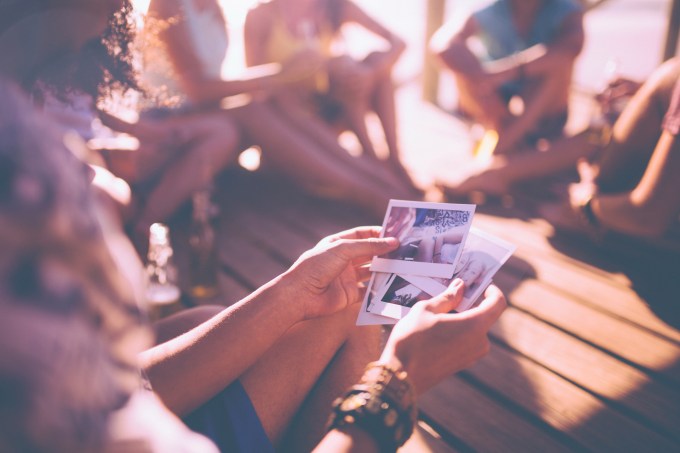 Friends looking at instant photographs of summer fun