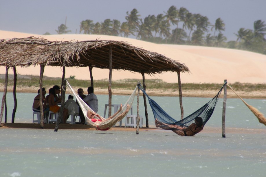 Turistas se refrescam no quiosque e nas redes dentro do mar na praia de Tatajuba, em Camocim, perto de Jericoacoara (CE)