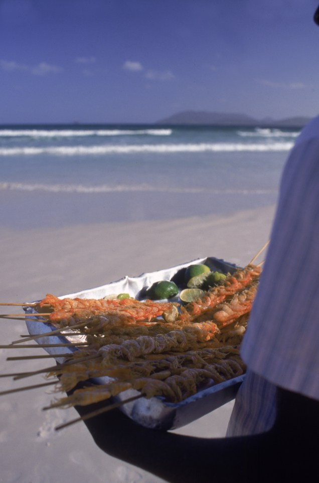 Garoto vendendo espeto de camarão numa praia de Cabo Frio (RJ)