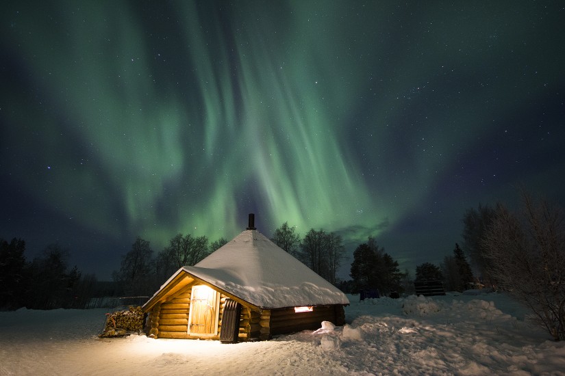 Um dos chalés do hotel e a aurora boreal ao fundo. (Foto: Divulgação)