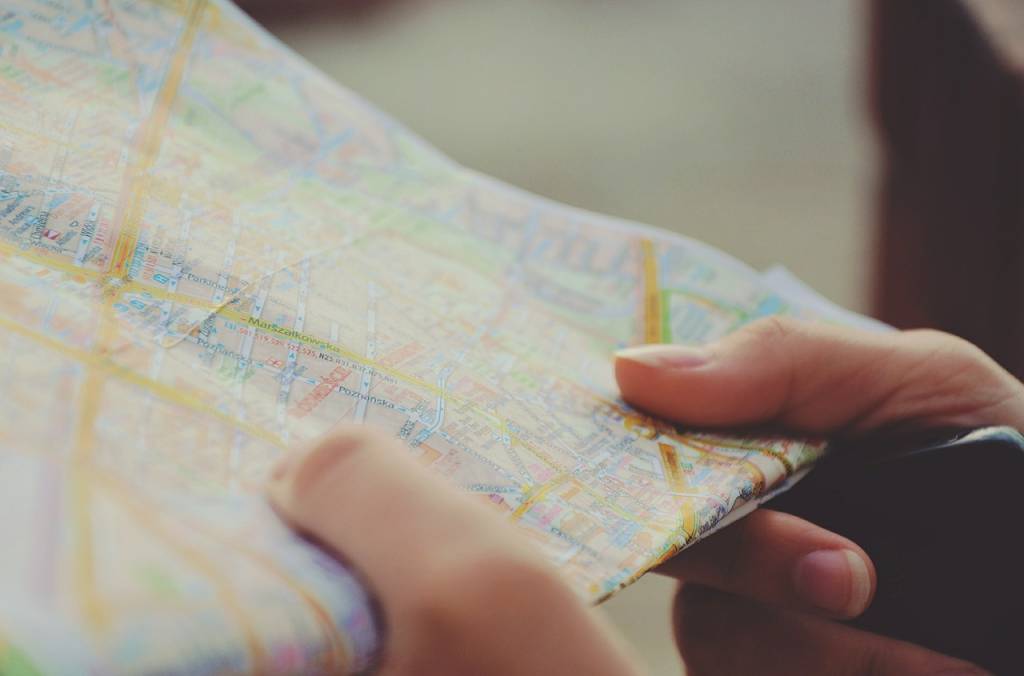 Mãos seguram mapa de papel e celular