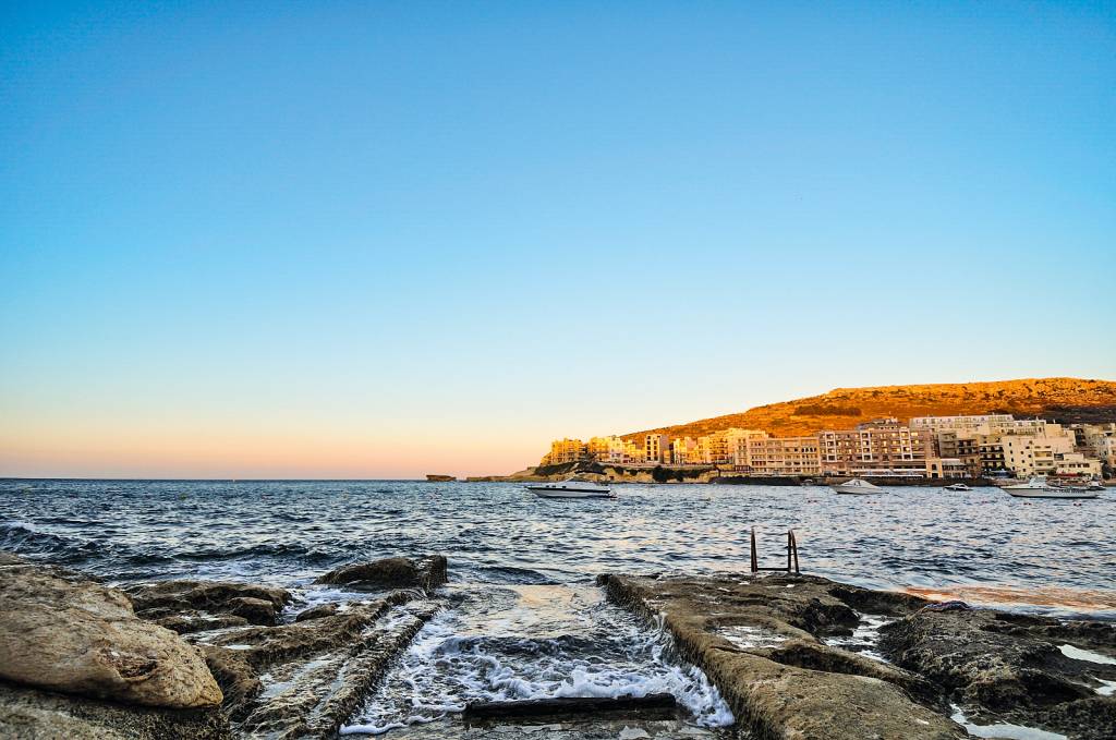 Vista para o mar sem praia, com uma cidade à distância