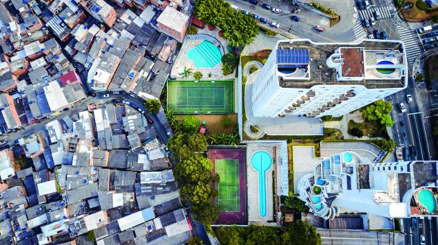 <span>Tuca Vieira é o fotógrafo responsável pela imagem definitiva sobre São Paulo. Talvez a contradição seja a maior característica da nossa cidade e dos paulistanos: a beleza e a feiura, a ordem e o caos, a pobreza e a riqueza, o pixo e o grafite, os fascistas e os libertários, o trânsito e as bicicletas, o Centro e a periferia, as múltiplas realidades que se empilham umas sobre as outras. São Paulo é um imenso campo de batalha, tanto do ponto de vista concreto quanto do simbólico. Tuca tirou a foto a bordo de um helicóptero, mostrando um muro dividindo as realidades tão opostas da favela de </span><span><b>Paraisópolis </b></span><span> </span><span>e as mansões empilhadas do </span><span><b>Morumbi</b></span><span>. Tive curiosidade de ver como, mais de dez anos depois, a tecnologia de um drone permitiria levar a mesma ideia a novos limites. Esta foto não é minha, apesar de o clique ter sido meu. Obrigado, Tuca.</span> <span>Tuca Vieira é o fotógrafo responsável pela imagem definitiva sobre São Paulo. Talvez a contradição seja a maior característica da nossa cidade e dos paulistanos: a beleza e a feiura, a ordem e o caos, a pobreza e a riqueza, o pixo e o grafite, os fascistas e os libertários, o trânsito e as bicicletas, o Centro e a periferia, as múltiplas realidades que se empilham umas sobre as outras. São Paulo é um imenso campo de batalha, tanto do ponto de vista concreto quanto do simbólico. Tuca tirou a foto a bordo de um helicóptero, mostrando um muro dividindo as realidades tão opostas da favela de </span><span><b>Paraisópolis </b></span><span> </span><span>e as mansões empilhadas do </span><span><b>Morumbi</b></span><span>. Tive curiosidade de ver como, mais de dez anos depois, a tecnologia de um drone permitiria levar a mesma ideia a novos limites. Esta foto não é minha, apesar de o clique ter sido meu. Obrigado, Tuca.</span>