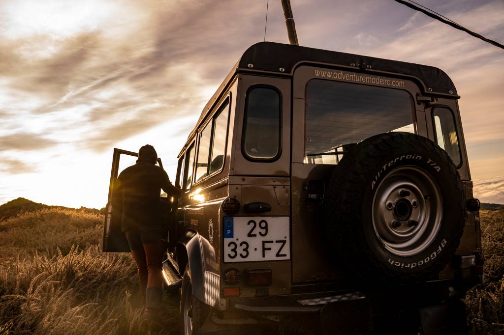 130 Jipe estacionado no alto da montanha, com o motorista do lado de fora a observar a paisagem, na Ilha da Madeira
