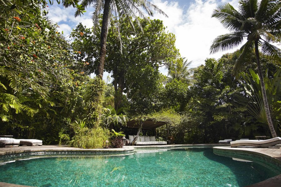 A piscina de quartzo verde é cercada por um jardim exuberante.