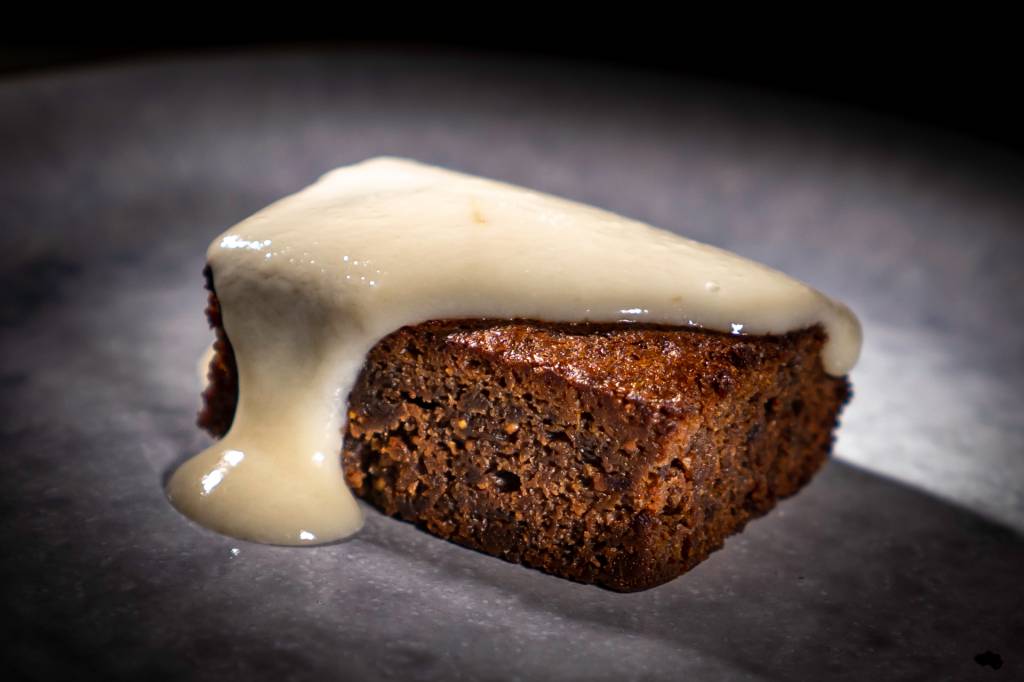 10 Pedaço retangular de bolo cor de chocolate, com uma calda branca escorrendo por cima