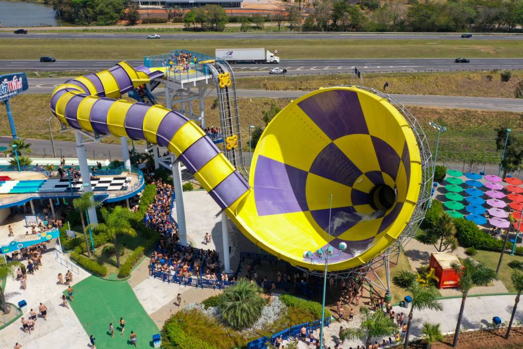 Wet’n Wild – Vortex A imagem mostra um enorme brinquedo amarelo e roxo que se parece com um escorregador e um funil