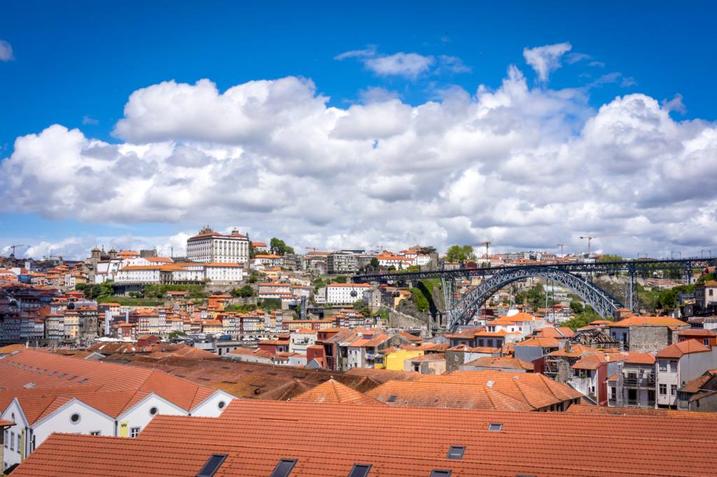 63 Telhadas em primeiro plano e, ao fundo, a Ponte D. Luís I e as casinhas coloridas da cidade do Porto