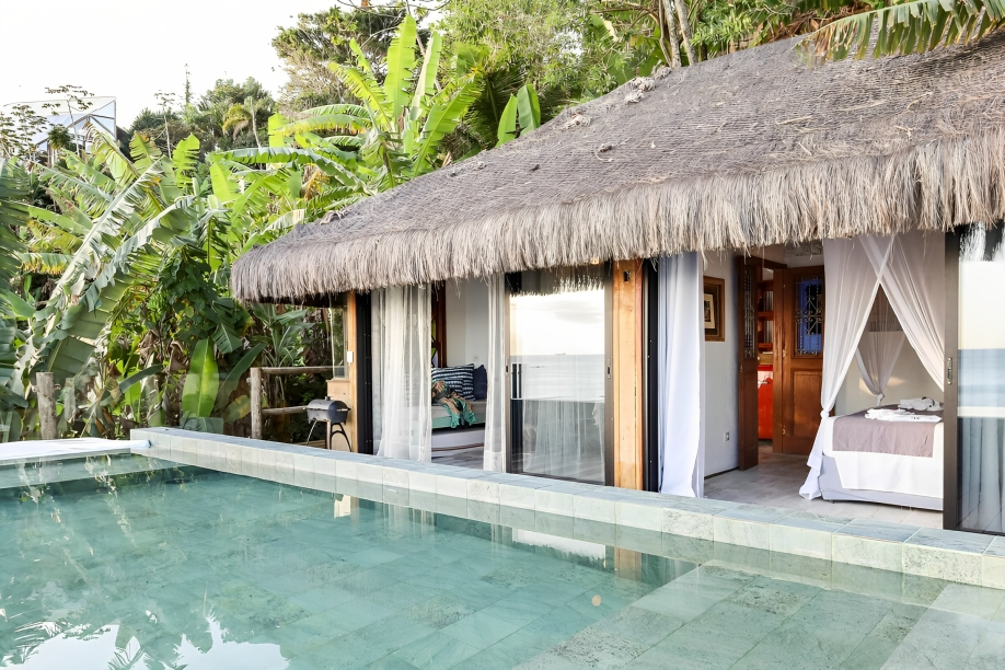 A imagem mostra uma piscina em frente a uma cabana com portas de vidro