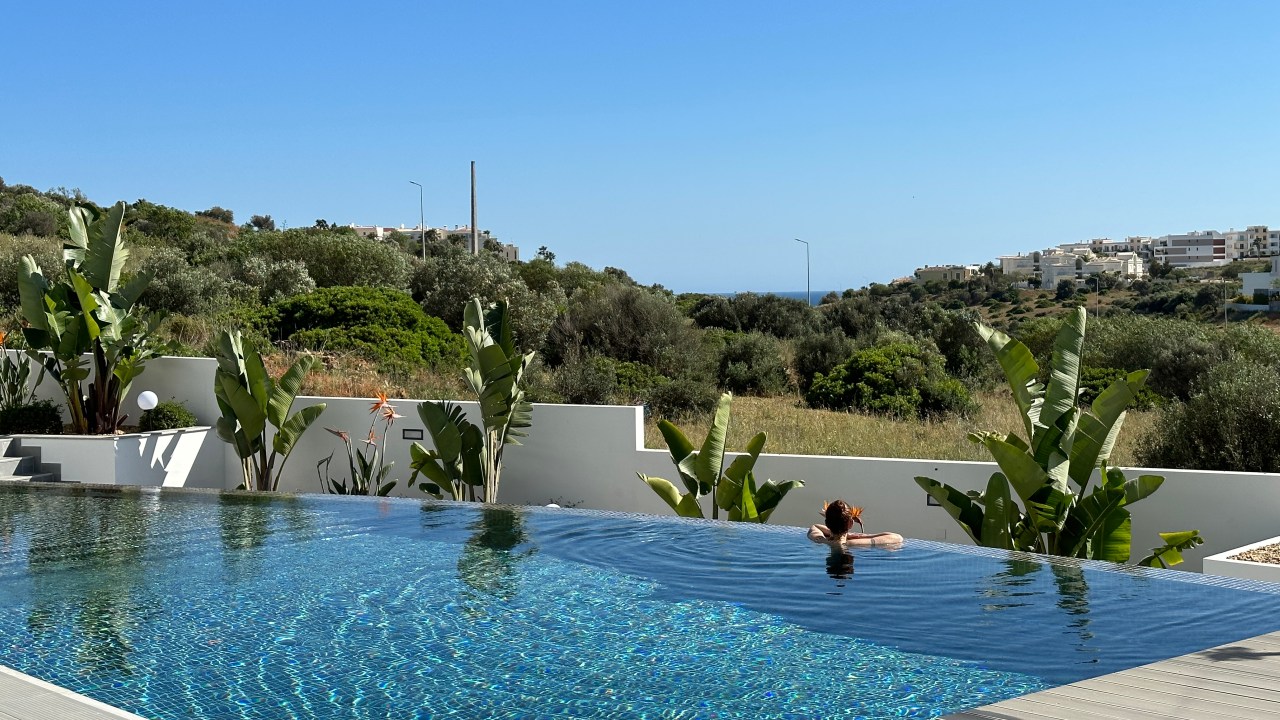 Piscina com borda infinita e uma pessoa apoiada numa das laterais