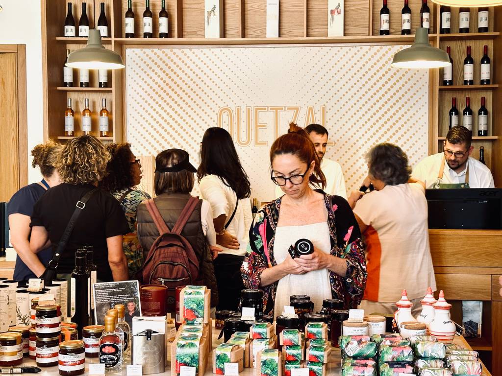 Mesa de uma loja cheia de produtos, com algumas pessoas a observá-los