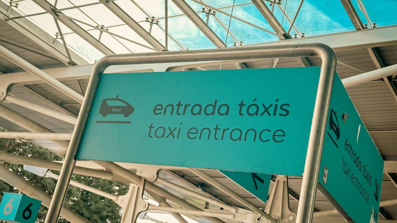 Imagem colorida com uma placa azul onde está escrito: entrada de táxis | taxi entrance