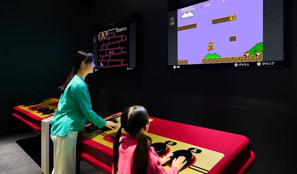 Nintendo Museum, Kyoto, Japão Uma mulher e uma criança se divertem jogando em um controle gigante no Nintendo Museum, Kyoto, Japão