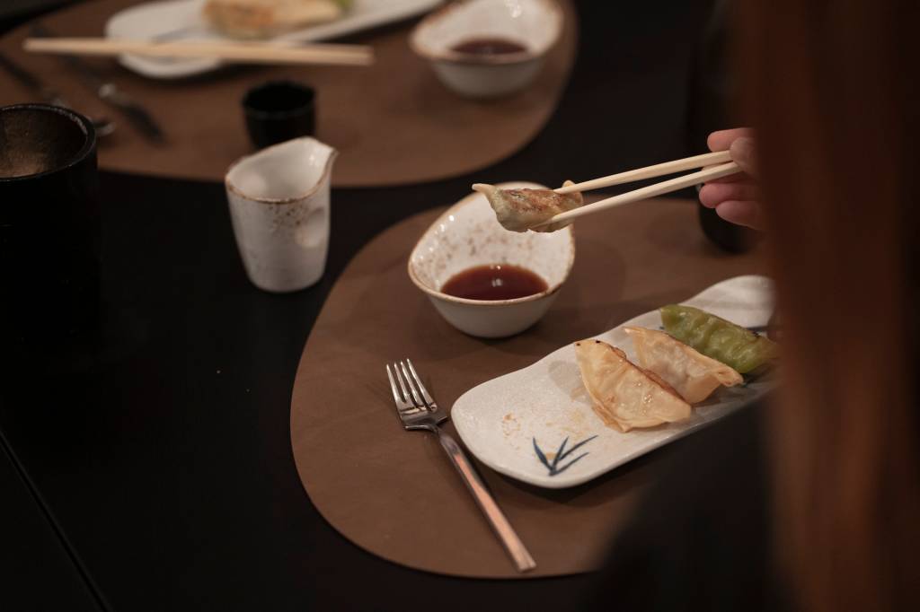 2024_Nuvem-399 Prato de gyozas servidos na mesa do restaurante Spices, com uma pessoa a comê-los com chopsticks