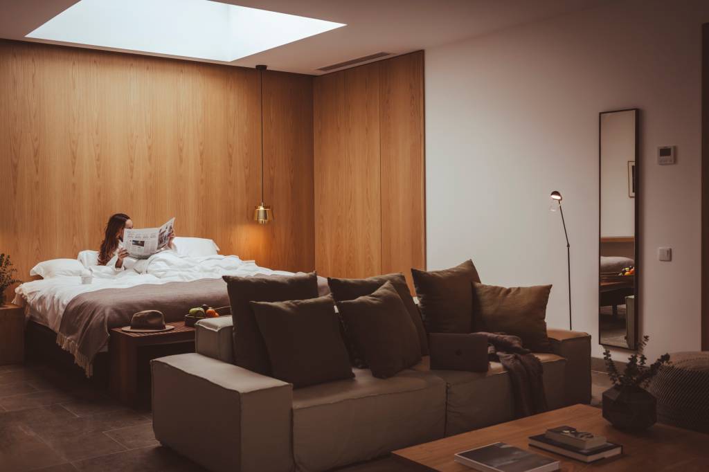 24 2 Imagem mostra o interior de um dos quartos do hotel, com uma mulher deitada na cama a ler o jornal