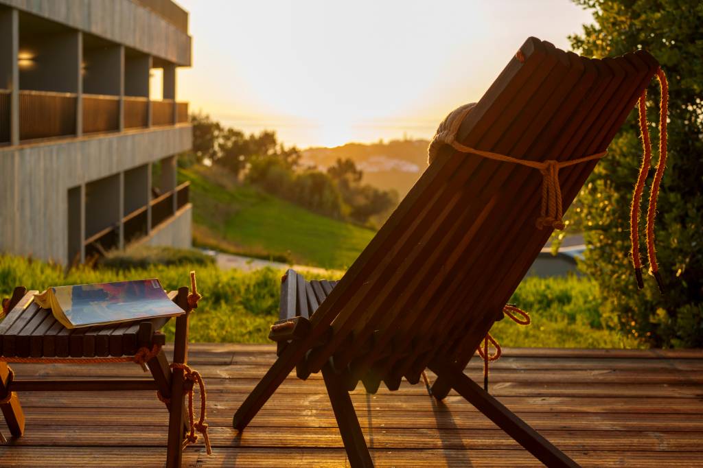 Varanda com uma cadeira e vista para o vale verde e o mar, no por do sol