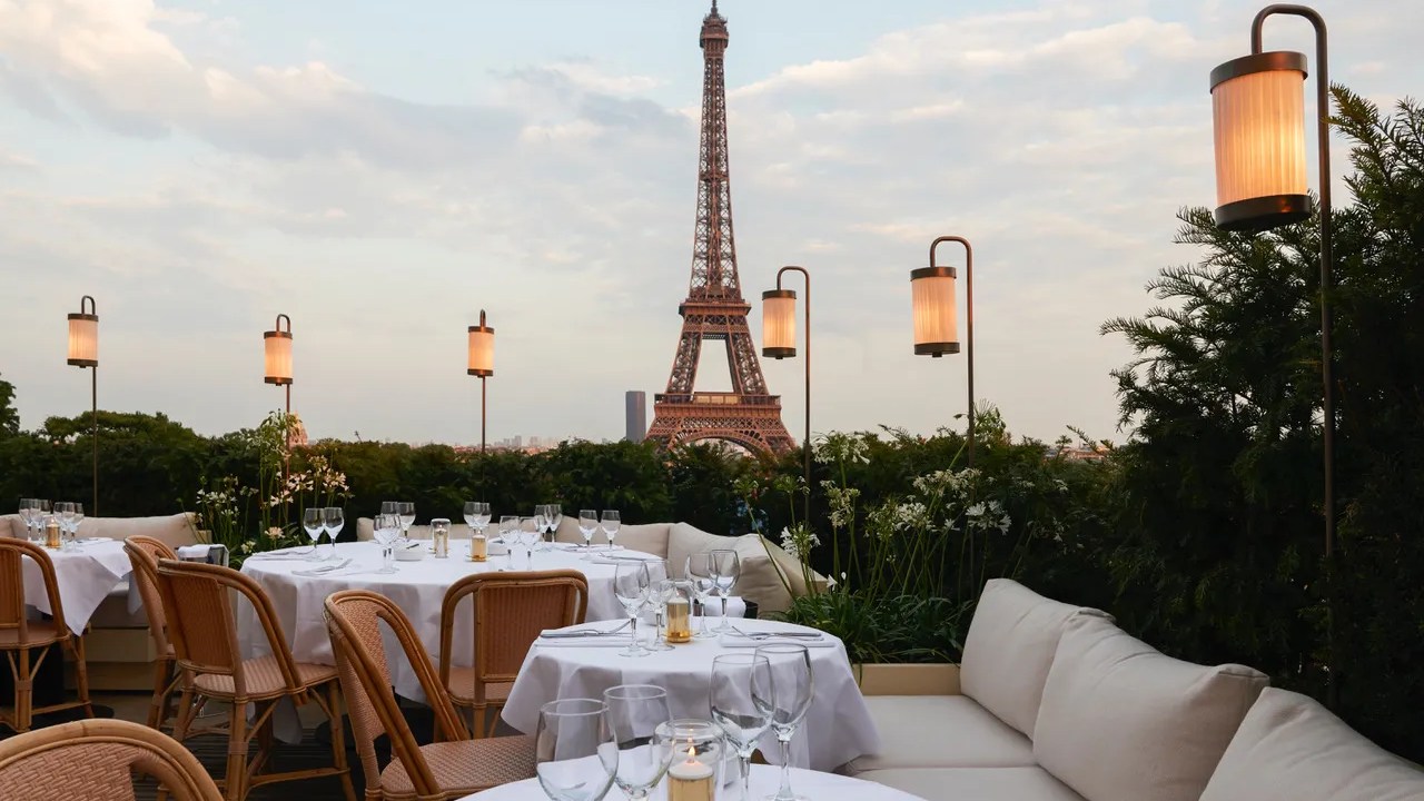 Terraço com mesas e cadeiras, com vista para a Torre Eiffel